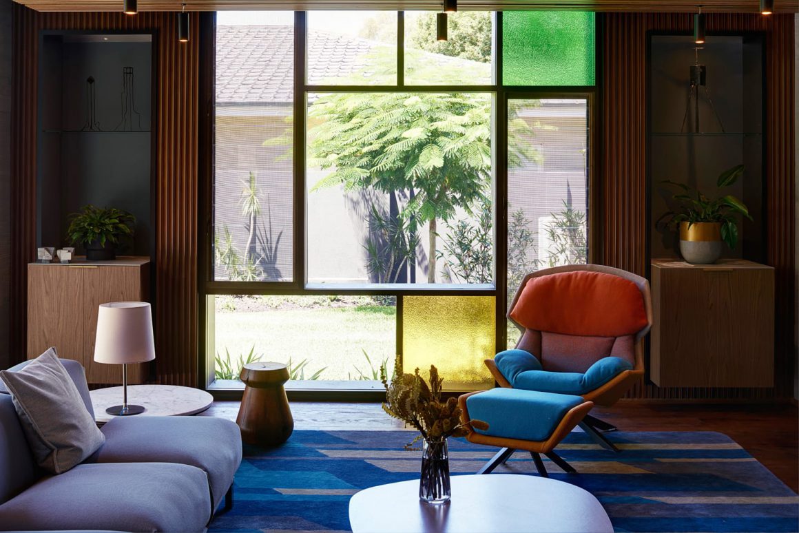 L'un des salons de la Roscommon House de Floreat avec un style rétro où se mêle accessoires asiatiques en bois ou bonzaï et sièges, tapis ou carreaux aux différentes couleurs dans un style Picasso. 