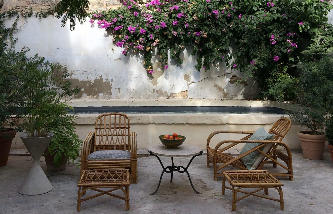 Salon de jardin avec deux chaises et deux repose-pieds en rotin pour une ambiance simple et rustique.